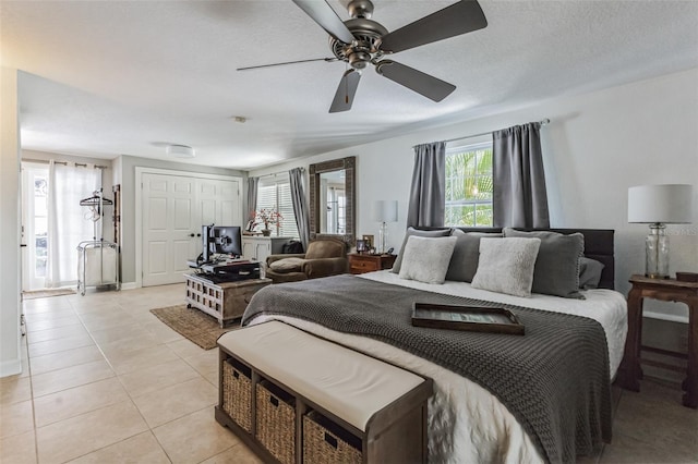 bedroom with ceiling fan, light tile patterned floors, a textured ceiling, and multiple windows