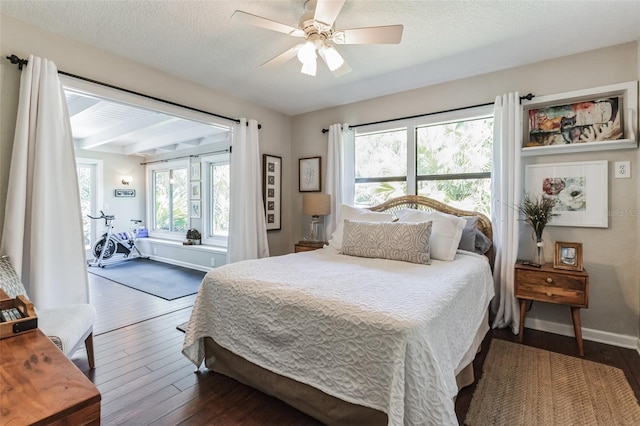 bedroom with a textured ceiling, multiple windows, dark wood-type flooring, and ceiling fan