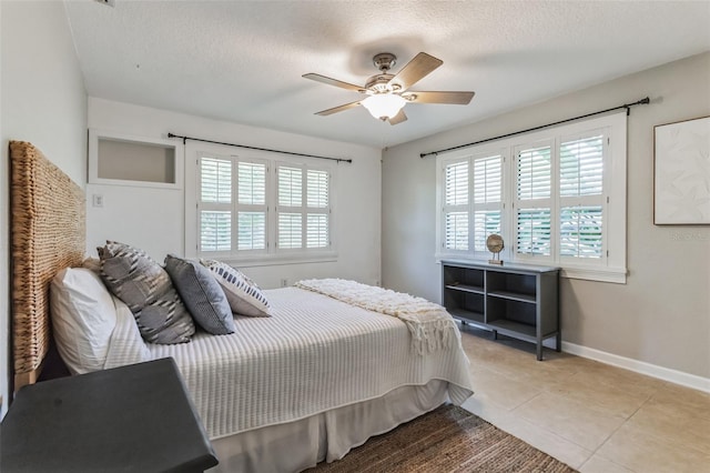 bedroom featuring ceiling fan, light tile patterned floors, and a textured ceiling