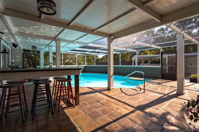 view of pool featuring glass enclosure, exterior bar, and a patio