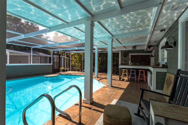 view of pool featuring glass enclosure, exterior bar, and a patio