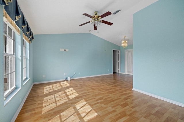 empty room with hardwood / wood-style floors, ceiling fan with notable chandelier, and vaulted ceiling