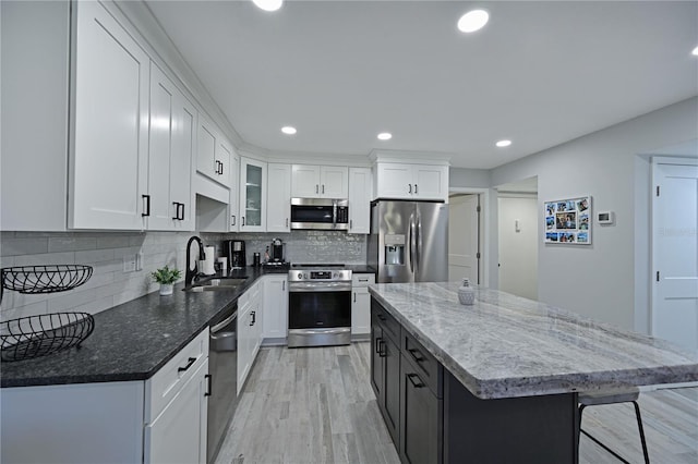 kitchen featuring white cabinets, stainless steel appliances, a kitchen island, and sink