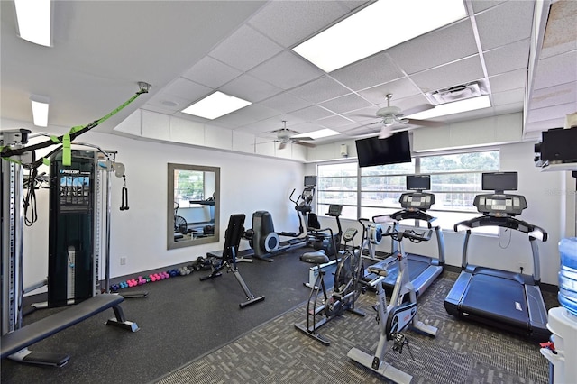 workout area featuring ceiling fan and a drop ceiling