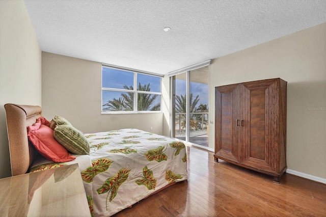 1800 Benjamin Franklin Dr Unit A304, Sarasota, FL 34236 - bedroom featuring wood finished floors, access to exterior, a textured ceiling, and baseboards