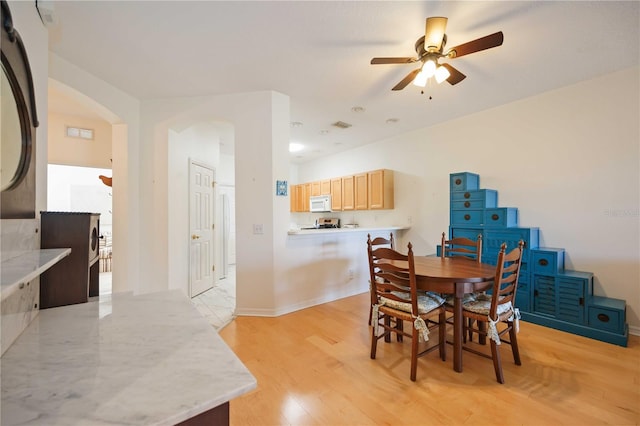 4209 Cascade Falls Dr, Sarasota, FL 34243 - dining space featuring arched walkways, a ceiling fan, light wood finished floors, and baseboards