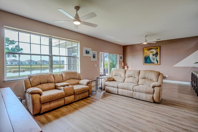 living room with a water view, light hardwood / wood-style flooring, and ceiling fan