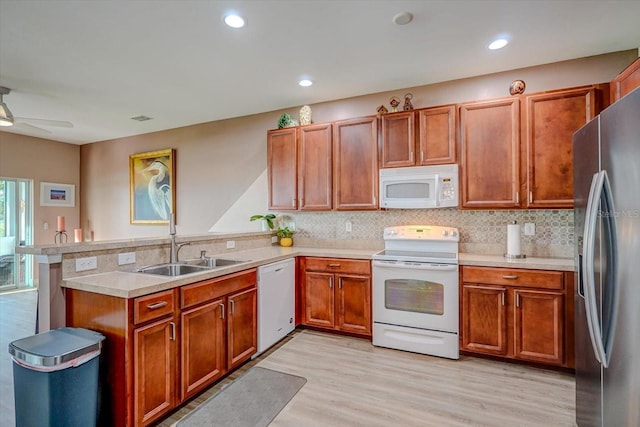 kitchen with kitchen peninsula, decorative backsplash, white appliances, sink, and light hardwood / wood-style flooring