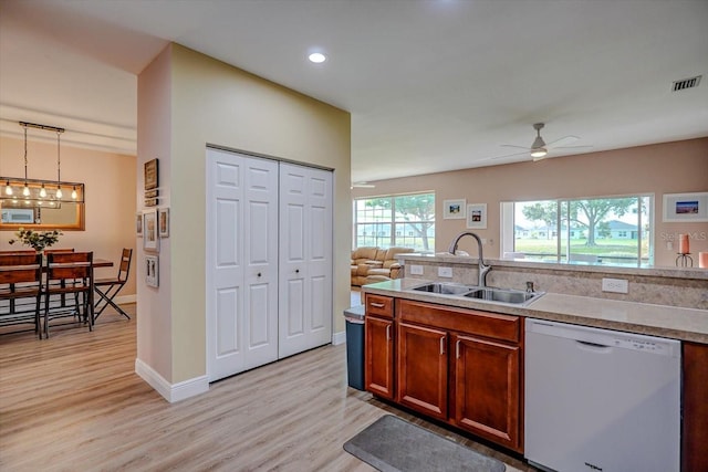 kitchen featuring dishwasher, sink, hanging light fixtures, light hardwood / wood-style flooring, and ceiling fan with notable chandelier