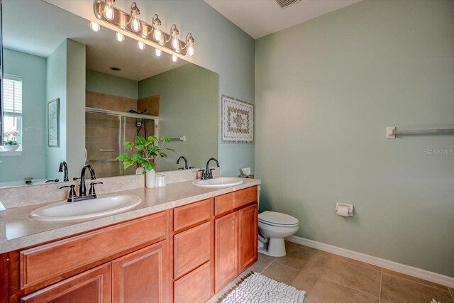 bathroom with tile patterned floors, vanity, toilet, and a shower with door