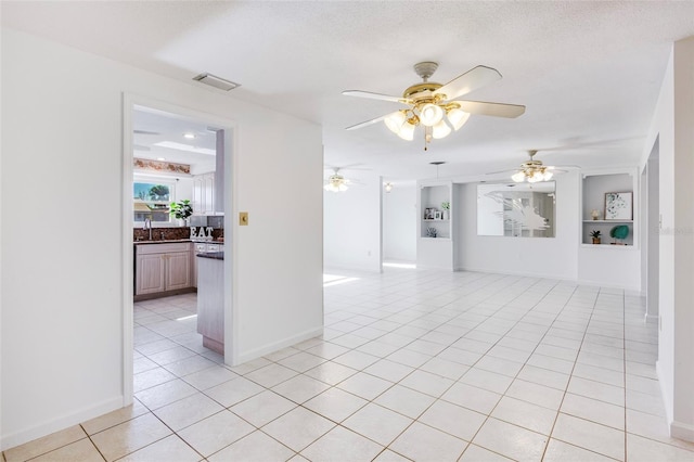 spare room with built in shelves, ceiling fan, sink, a textured ceiling, and light tile patterned floors