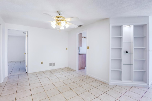 tiled empty room with ceiling fan and a textured ceiling