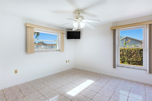 tiled empty room with ceiling fan and a healthy amount of sunlight