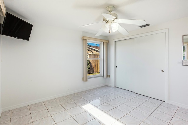 unfurnished bedroom with multiple windows, a closet, ceiling fan, and light tile patterned flooring