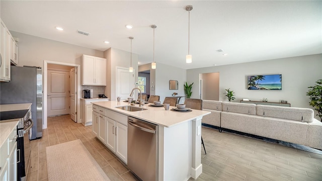 kitchen featuring sink, white cabinets, stainless steel appliances, and decorative light fixtures