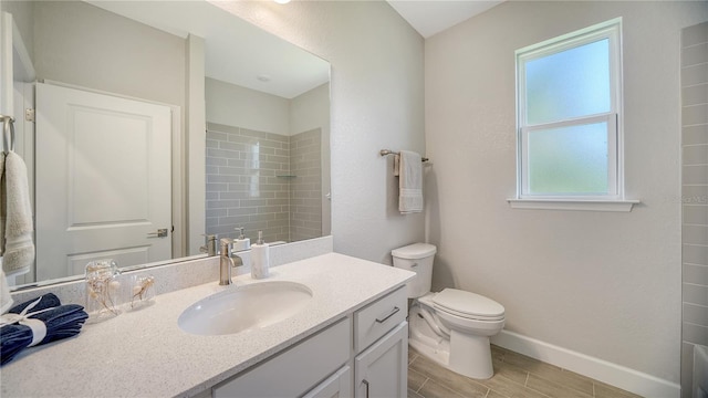 bathroom with tiled shower, vanity, and toilet