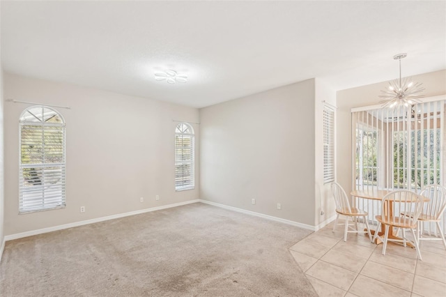 empty room featuring a healthy amount of sunlight, light carpet, and a chandelier