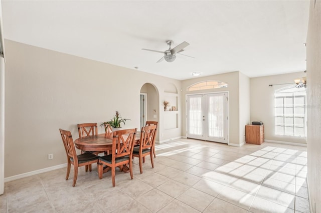 tiled dining area with plenty of natural light, ceiling fan with notable chandelier, and french doors