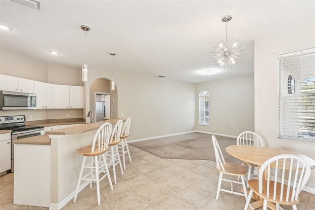 kitchen with a chandelier, white cabinets, pendant lighting, and appliances with stainless steel finishes