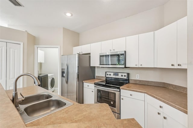 kitchen featuring white cabinets, washing machine and dryer, stainless steel appliances, and sink