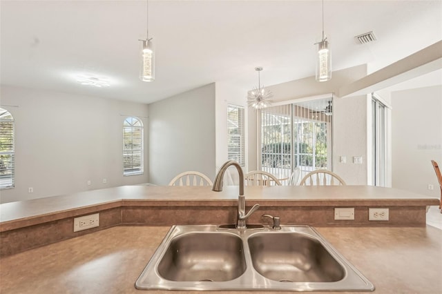 kitchen with pendant lighting, sink, a healthy amount of sunlight, and an inviting chandelier