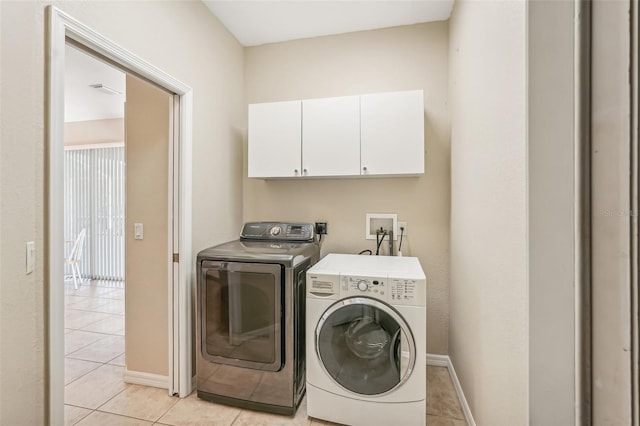 laundry area featuring cabinets, light tile patterned floors, and washing machine and dryer