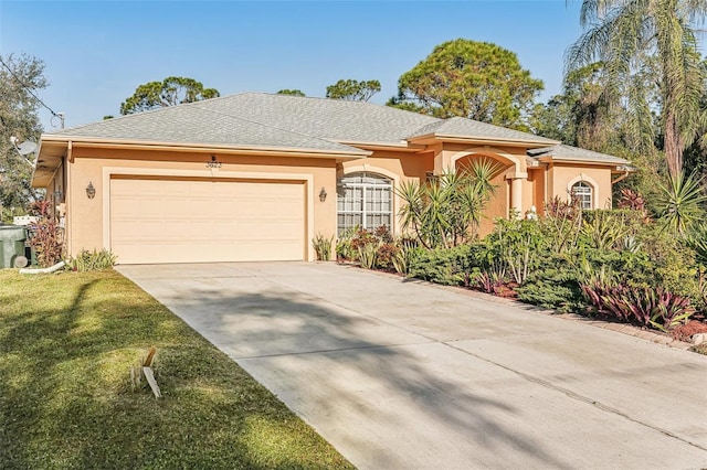 view of front of house featuring stucco siding, an attached garage, concrete driveway, and a front lawn