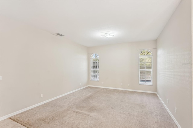 spare room with baseboards and light colored carpet