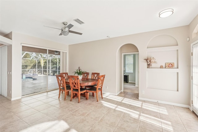 dining room with a ceiling fan, arched walkways, light tile patterned floors, and baseboards