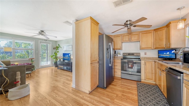 kitchen with appliances with stainless steel finishes, light brown cabinetry, light hardwood / wood-style floors, and pendant lighting