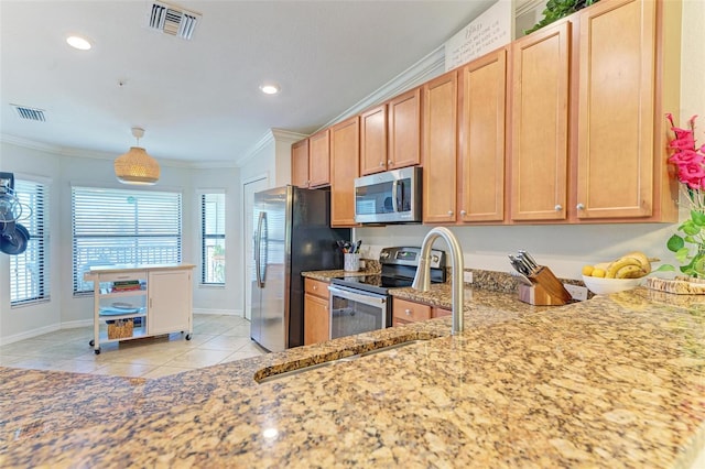 kitchen with ornamental molding, appliances with stainless steel finishes, light stone countertops, and light tile patterned floors