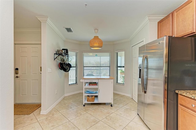 kitchen with crown molding, light stone countertops, light tile patterned flooring, and stainless steel fridge