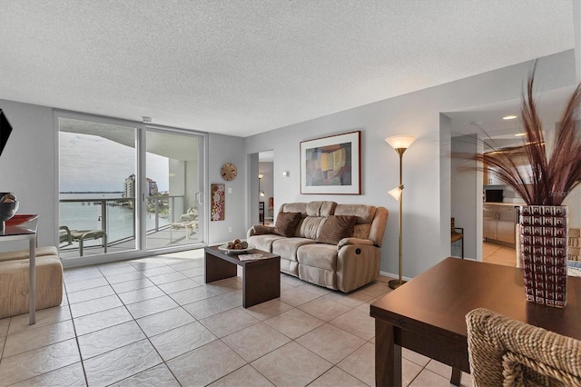 living room with light tile patterned floors, a textured ceiling, a water view, and floor to ceiling windows