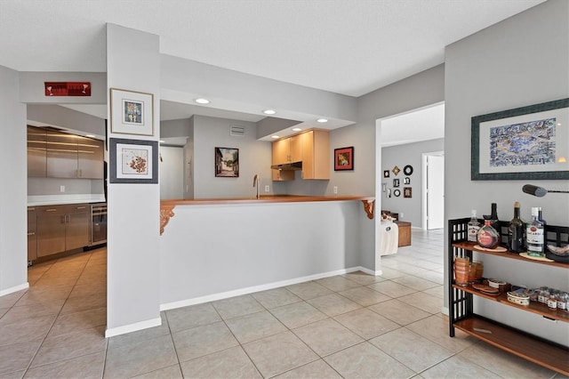 kitchen with kitchen peninsula, wine cooler, light tile patterned floors, and a textured ceiling