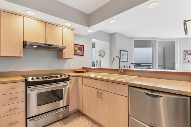 kitchen featuring sink, stainless steel appliances, kitchen peninsula, light brown cabinetry, and light tile patterned floors