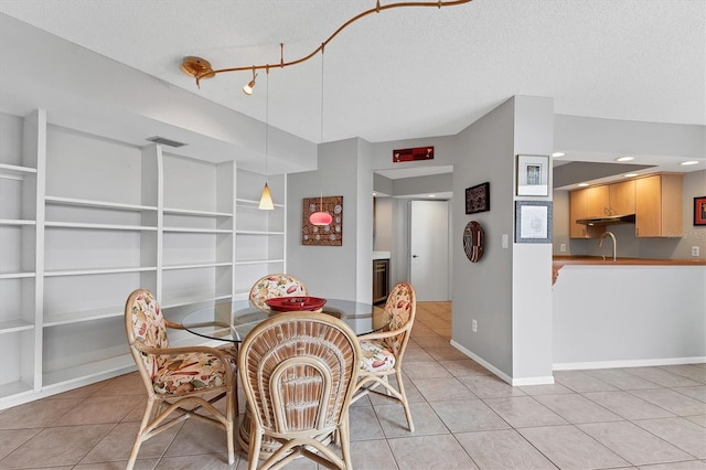 tiled dining area with sink and a textured ceiling