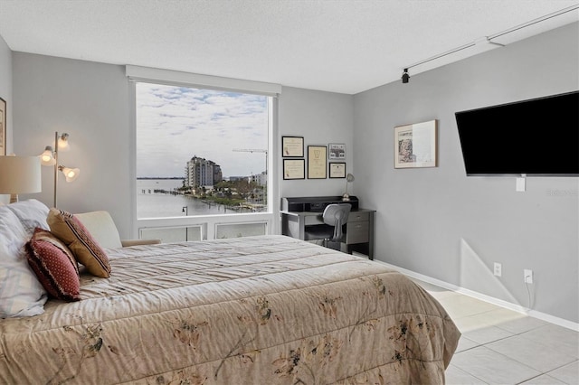 bedroom featuring multiple windows, light tile patterned floors, and a textured ceiling