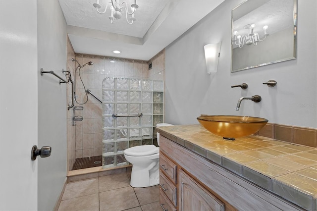 bathroom featuring a tile shower, tile patterned flooring, a textured ceiling, toilet, and vanity