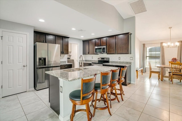 kitchen featuring appliances with stainless steel finishes, dark brown cabinets, a center island with sink, and sink