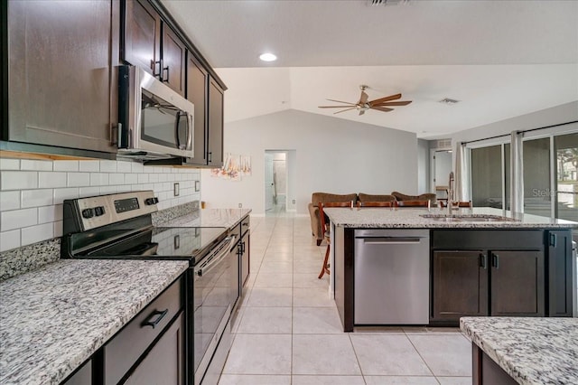 kitchen with lofted ceiling, stainless steel appliances, sink, ceiling fan, and light stone counters