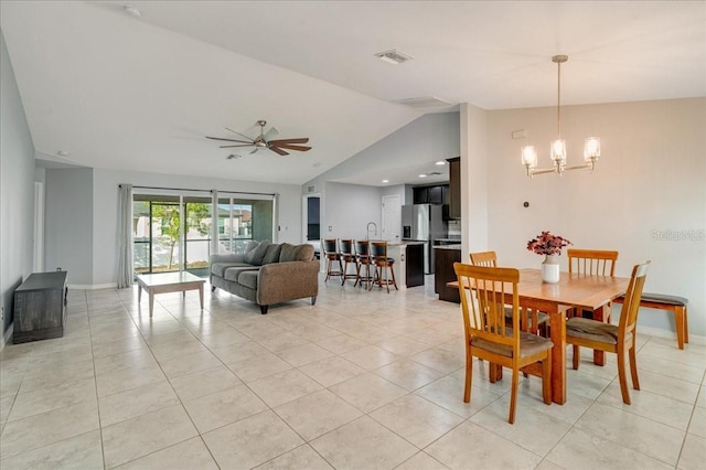 tiled dining space featuring lofted ceiling and ceiling fan with notable chandelier