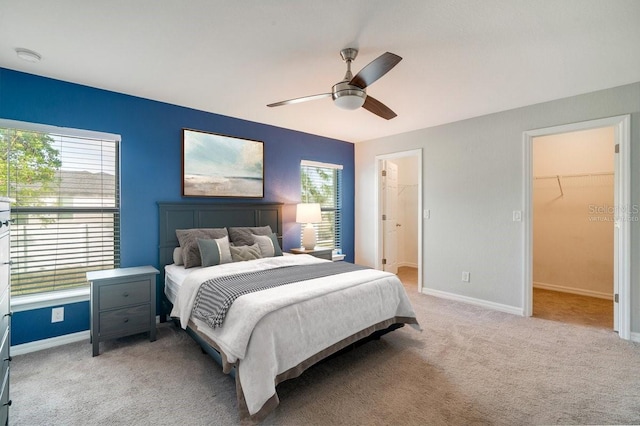 carpeted bedroom with ceiling fan, a closet, a spacious closet, and multiple windows