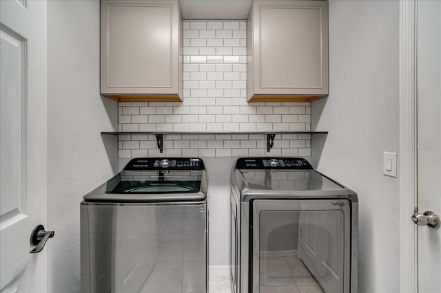 laundry area featuring cabinets, light tile patterned floors, and washing machine and clothes dryer