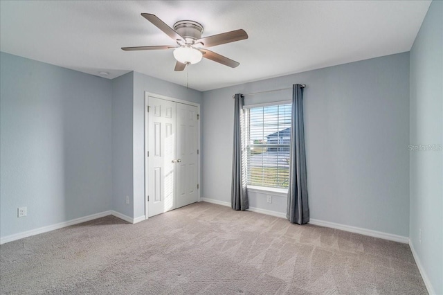 unfurnished bedroom featuring ceiling fan, light colored carpet, and a closet