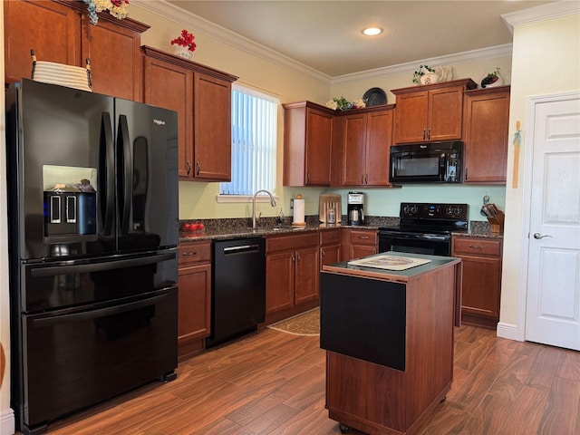 kitchen featuring dark hardwood / wood-style floors, ornamental molding, a kitchen island, black appliances, and sink