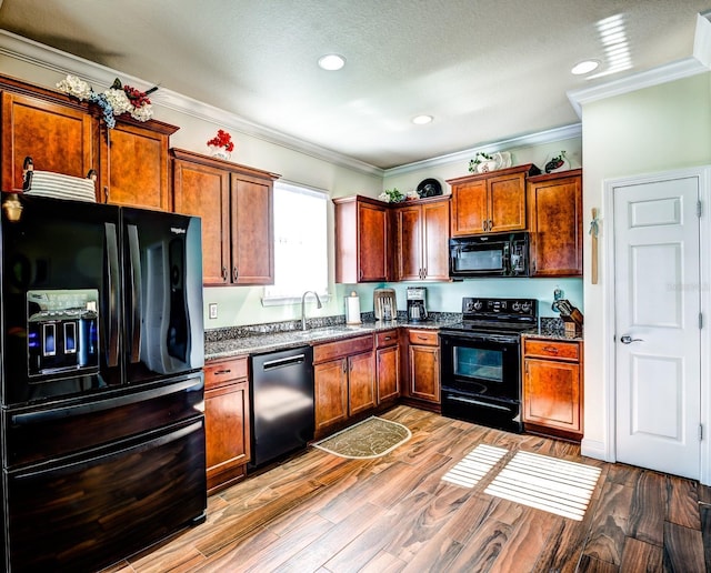 kitchen featuring light wood-type flooring, crown molding, sink, and black appliances