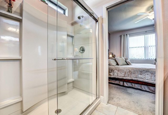 bathroom featuring ceiling fan, a textured ceiling, a shower with door, and tile patterned flooring