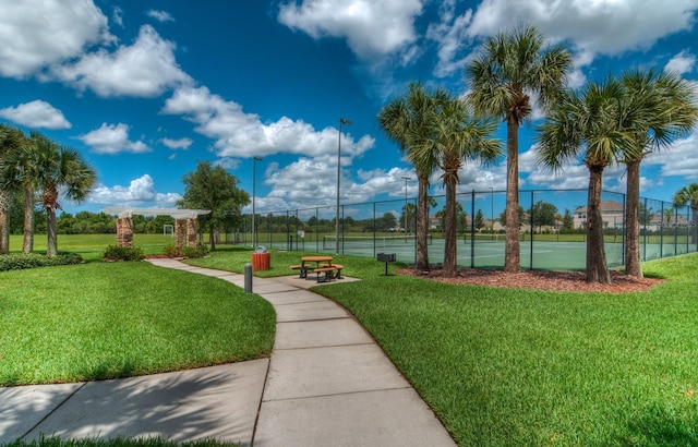 surrounding community with tennis court, a yard, and a water view