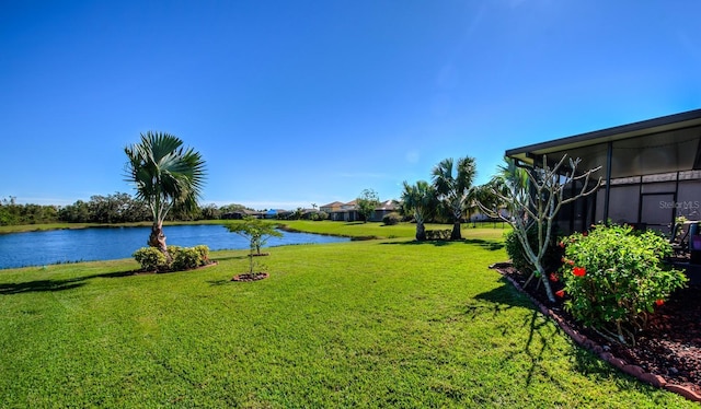 view of yard with a sunroom and a water view