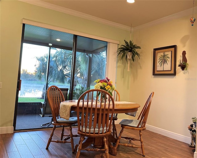 dining room featuring dark wood-type flooring, baseboards, and ornamental molding